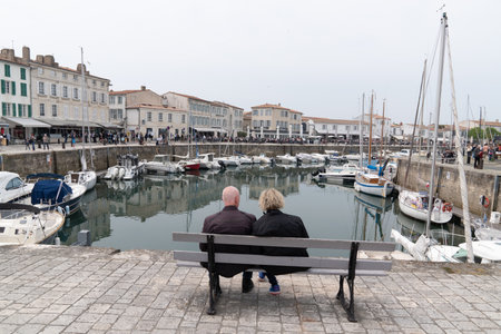 Saint Martin de  RÃ©, Charente Maritime / France - 05 01 2019 : retirement couple senior sit on bench in harbor St Martin in Island Ile de Reのeditorial素材