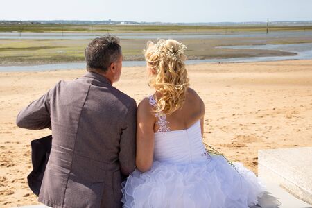 Beach Wedding with Beautiful Bride and Groom sitting Coastlineの写真素材