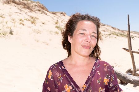 Portrait of mature woman resting on the nature dunes sand beach smile happyの写真素材