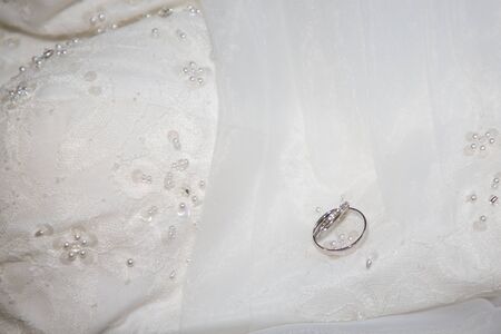 wedding rings on a sparkling white marriage dress backgroundの写真素材