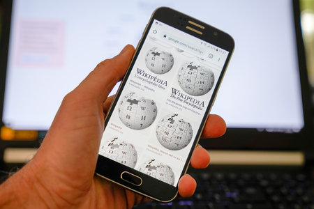 Bordeaux , Aquitaine / France - 10 11 2019 : man hand holding Wikipedia logo on smartphone free encyclopedia siteのeditorial素材