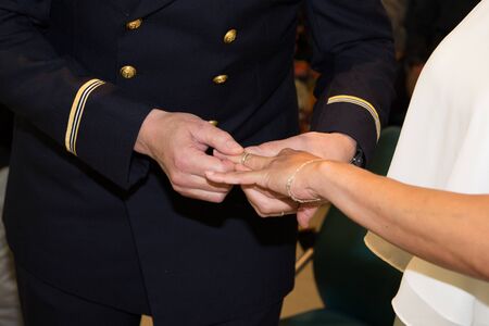 Male soldier putting engagement ring on girlfriends finger wedding bride groom marriageの写真素材