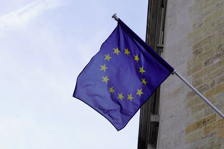 eu Flag of European Union waving in wind on flagpole building against sky with clouds on sunny day