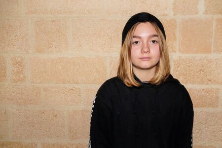 Portrait of serious Caucasian teenager girl brick stone wall backgroundの写真素材