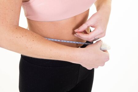 sporty woman measuring her slim body in white isolated background