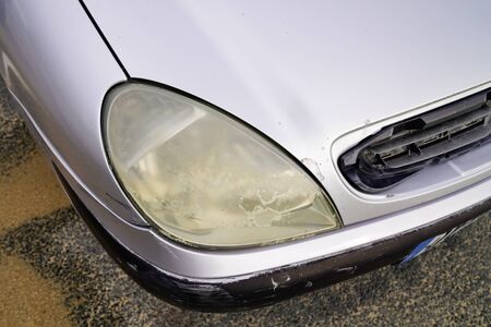 Close up hazy yellowed dirty car unpolished cloudy foggy front plastic automobile headlight wornの写真素材