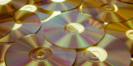 Yellow compact discs background warm Cd Dvd Blue ray laid out on a flat surfaceの写真素材