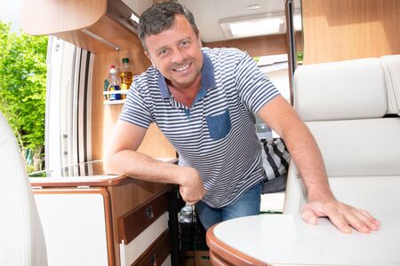 Man happy vanlifer smiling in interior Motor Home campervan for roadtrip vacationの写真素材