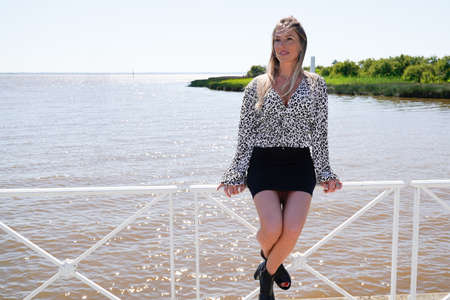 Young woman relaxing at the seaside sitting on a railingの写真素材