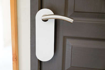Entrance white door hanger of hotel room with empty sign please do not disturbの写真素材