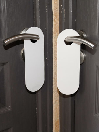 Sign on two white door hanger handle with empty plate do not disturbのeditorial素材