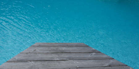 wooden board around the blue water of swimming poolの写真素材