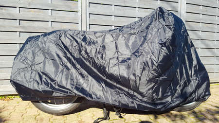 motorcycle protected by silver and blue bike protective cover in street motorbike with tarpaulin jacketの写真素材