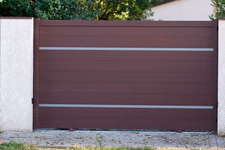 portal brown bordeaux metal of driveway entrance gates set in modern new houseの写真素材