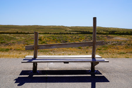 Old empty wooden bench on pathway access sandy beachの写真素材