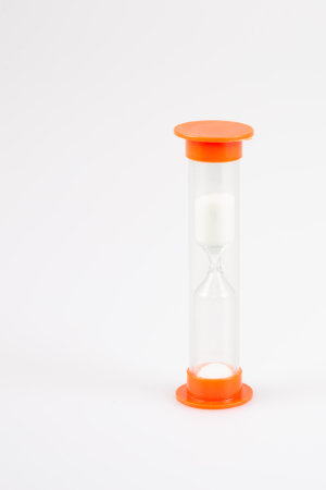 hourglass timer in plastic orange in gray background with white sand