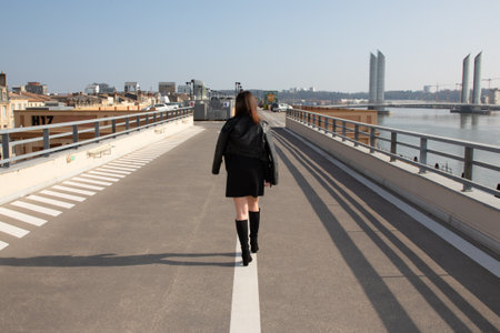 Girl is walking alone on road city on dividing strip line in back behind viewの写真素材