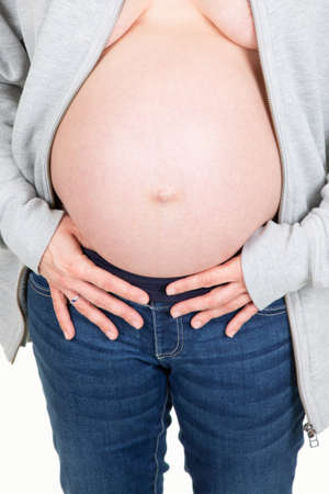 belly of a pregnant woman dressed in an open gray vest and jeansの写真素材