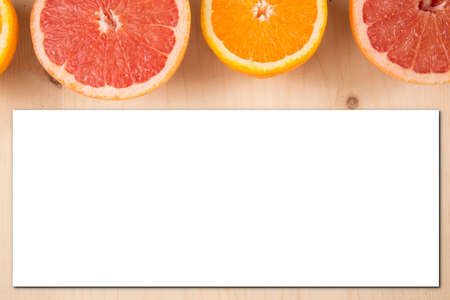 juicy slices of orange grapefruit on wooden background for menu top view and blank greeting card paper empty invitation recipe space for text concept of vegetarian vitamin and healthy foodの写真素材