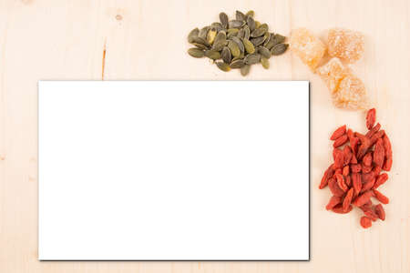 mock up of an empty white sheet on a wooden background with heaps of seeds as decoration Background mock up with a place for text copy spaceの写真素材