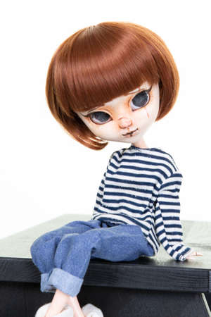 doll girl sit on black wooden bench over white background fashion toy childの写真素材