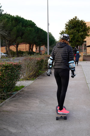 young girl rear view from behind woman rides a skateboard city concept of sports lifestyle and...