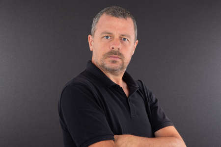 Portrait of serious arms crossed mature man on gray background