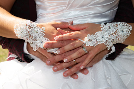 wedding rings on bride and groom fingers hands on marriage white dress background during outdoor celebrationの写真素材