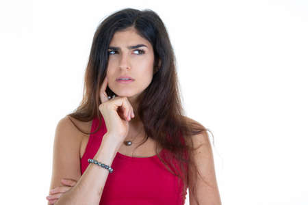 young woman thinking looks side hand on chin looking aside copy space empty white backgroundの写真素材