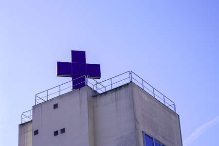 hospital building facade with big roof blue crossの写真素材