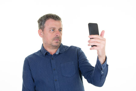 man making smartphone selfie with cell phone on white background middle aged handsome guy portraitの写真素材