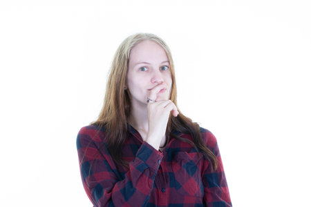 portrait of cute young woman holding hand on cheek looking suspicious posing against white...
