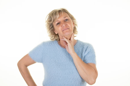 pensive senior woman portrait blue eyes hand on chin on white backgroundの写真素材