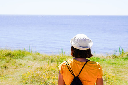 sporty woman with backpack walking on beach coast looking water beach
