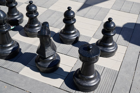 black pieces of a chess set on the giant board on the ground in the street townの写真素材
