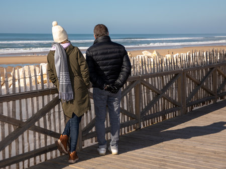 man woman winter tourist couple middle aged in vacation on coast beach sea looking horizon oceanの写真素材
