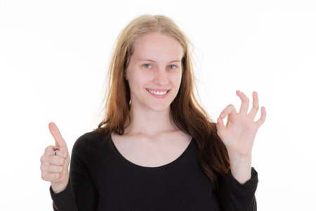 Portrait of happy smiling young woman showing thumbs up palm and ok fingers gestureの写真素材
