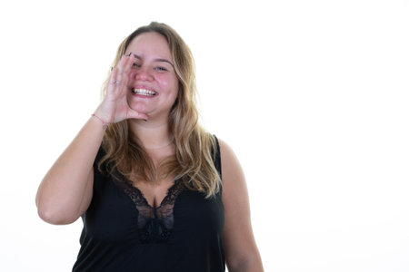 Beautiful woman in casual clothes black shirt screams and speaks loudly with her hand in amplifier