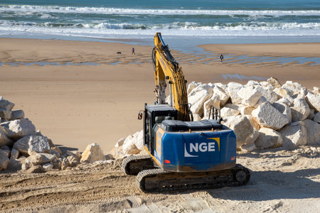 Bordeaux , Aquitaine France - 04 10 2023 : NGE Guintoli Excavator shifts stones on the beach in preparation for tourism beach seasonのeditorial素材