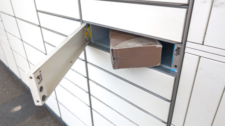 Modern parcel locker with many postal boxes outdoors and open box with cardboard ready to send...