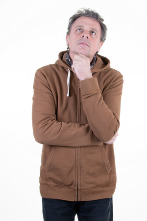 handsome middle age man pensive thinking looking up on white background wearing sporty brown hoodyの写真素材