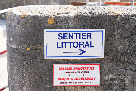 Sentier littoral means coastal path in text French sign with arrow coastal trail direction and dangerous cliffs with risk of falling rocks in Franceの写真素材