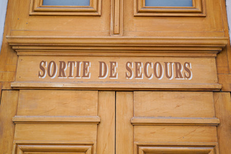 emergency exit french text sign painted on old door wooden means emergency exit fire escapeの写真素材