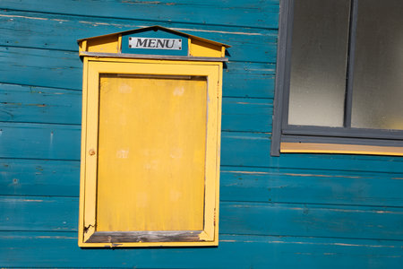 Blank yellow restaurant menu empty vintage mockup signboard on facade wooden blue bar wall