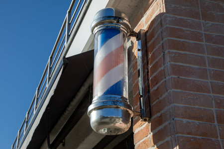 Classic gentleman red white and blue striped vibe for traditional barber shop barbershop pole attached to a brick wallの写真素材