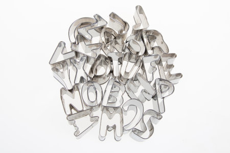 Small die-cut letters mold cut from steel with a laser cutter stacked randomly in a pile on a white backgroundの写真素材