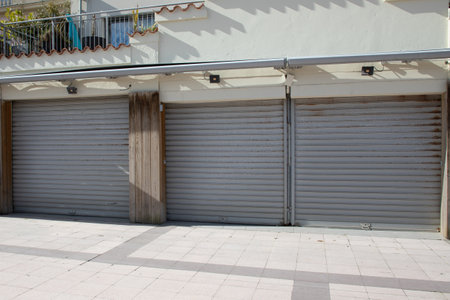 three industrial building facade closed 3 gray roller shutter gateの写真素材