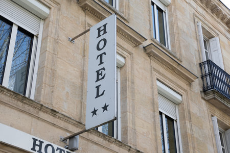 Hotel sign text capital letters attached to facade wall high building entrance with two 2 stars in city centerの写真素材