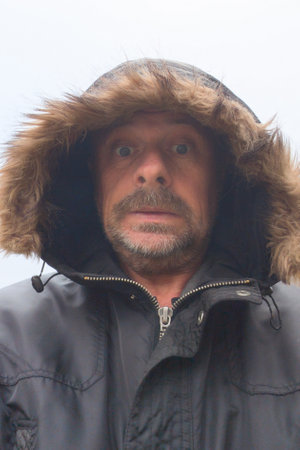 outdoor winter portrait of middle aged bearded man with hood vest hat outside fresh day