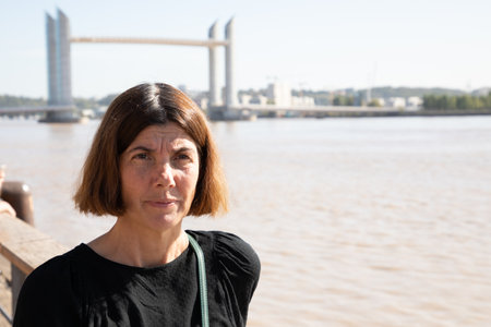 brunette woman standing on the quay with great view on french bordeaux city with bob hairsの写真素材
